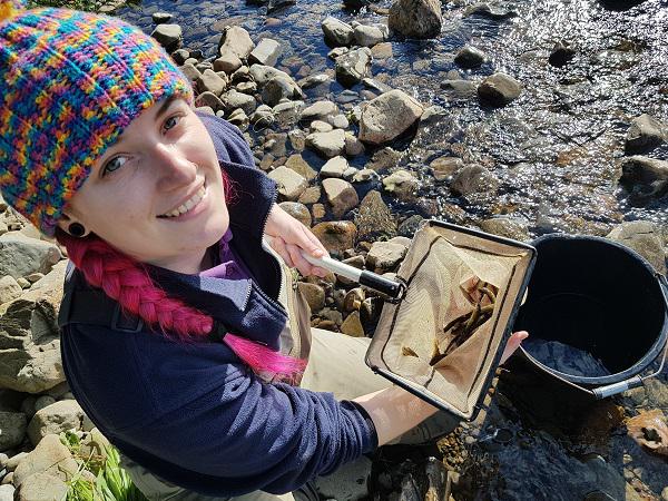 All smiles as Kacie presents a net full of Polmaddy Burn salmon fry